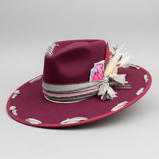Maroon hat with decorative elements on a wooden background